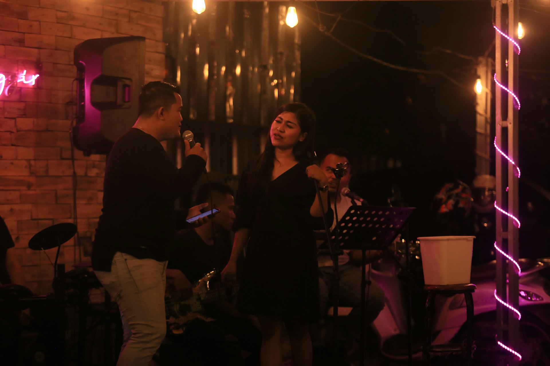 A man and woman singing on stage with a band